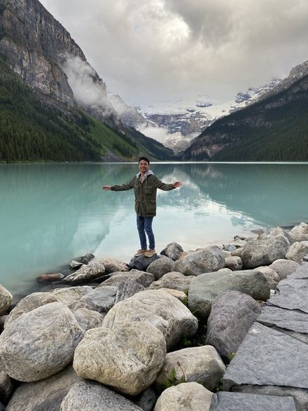 Standing on the rocks with arms outstretched in front of Lake Louise