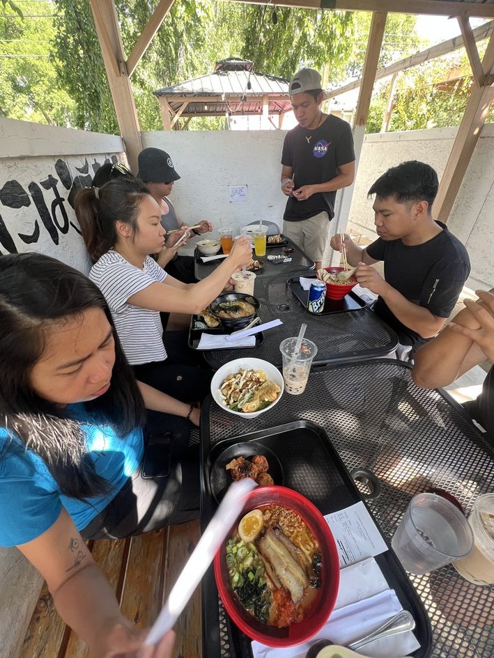 Huge group sitting on a patio eating ramen