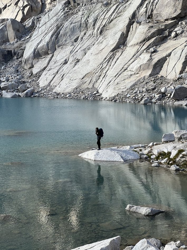 Standing on a white rock surrounded by crystal clear alpine water