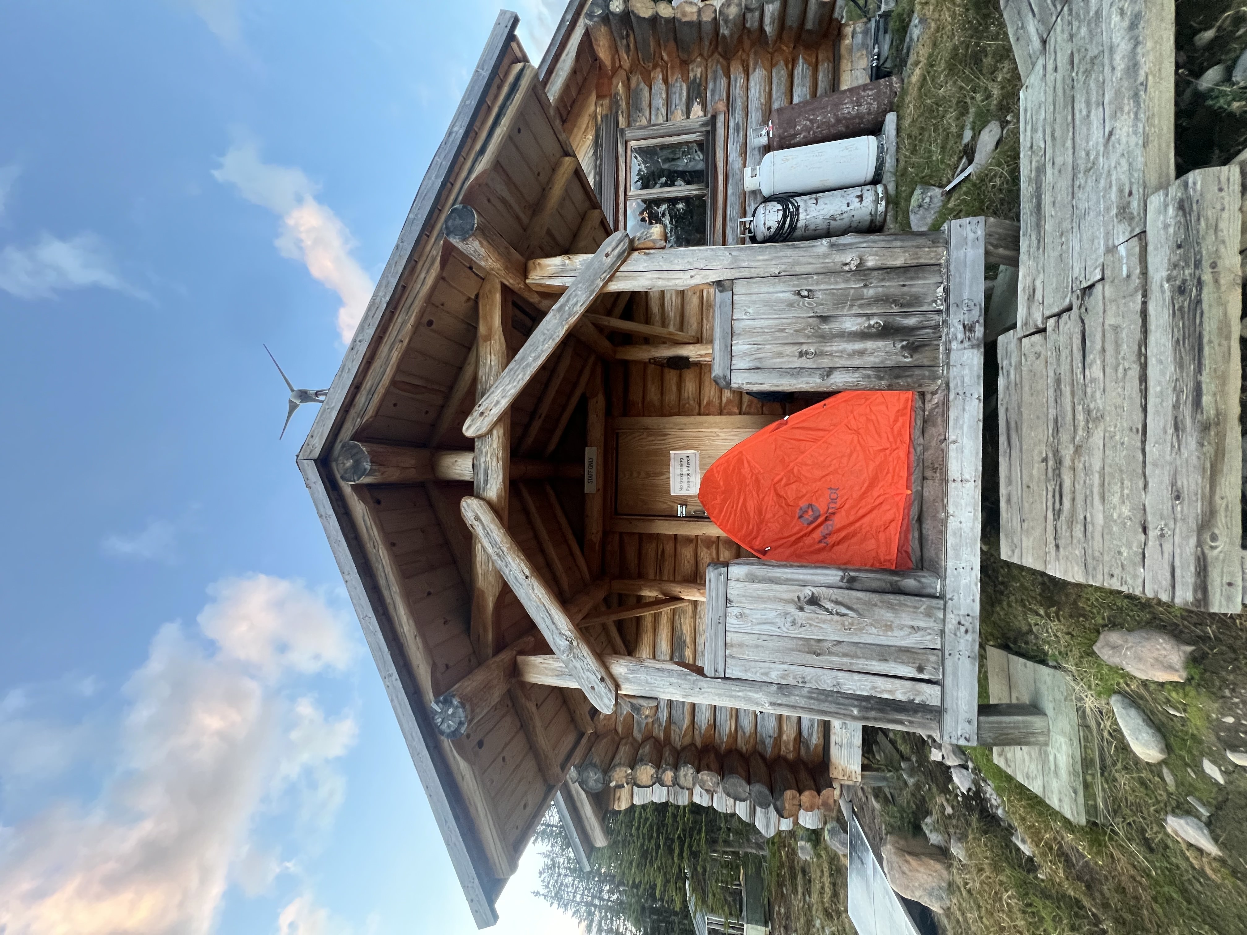 Hiker in front of a log cabin shelter