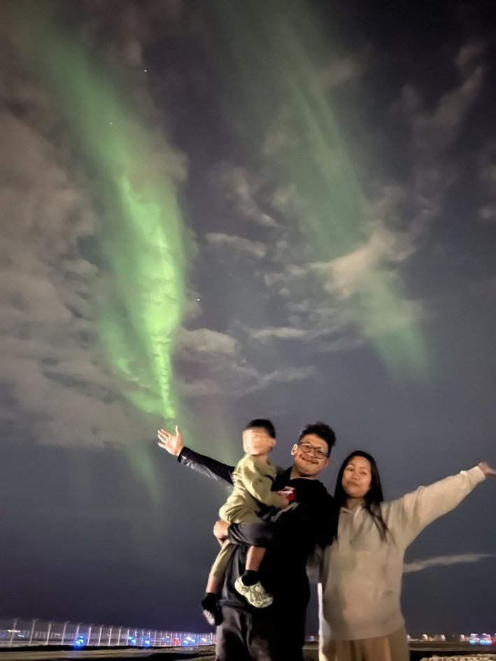 Family standing under the aurora