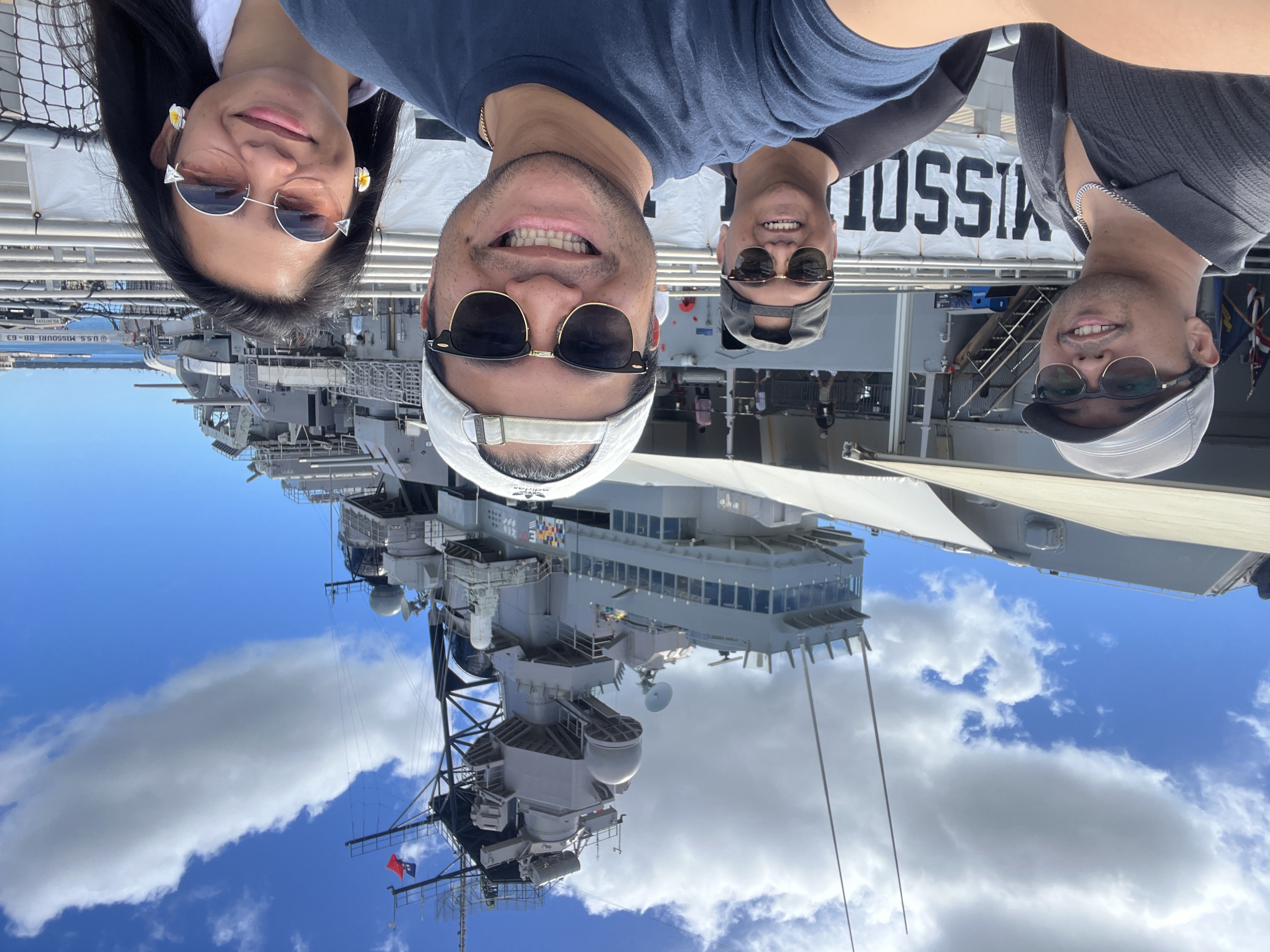 A group selfie on the USS Missouri, the superstructure and a Missouri banner behind four people.