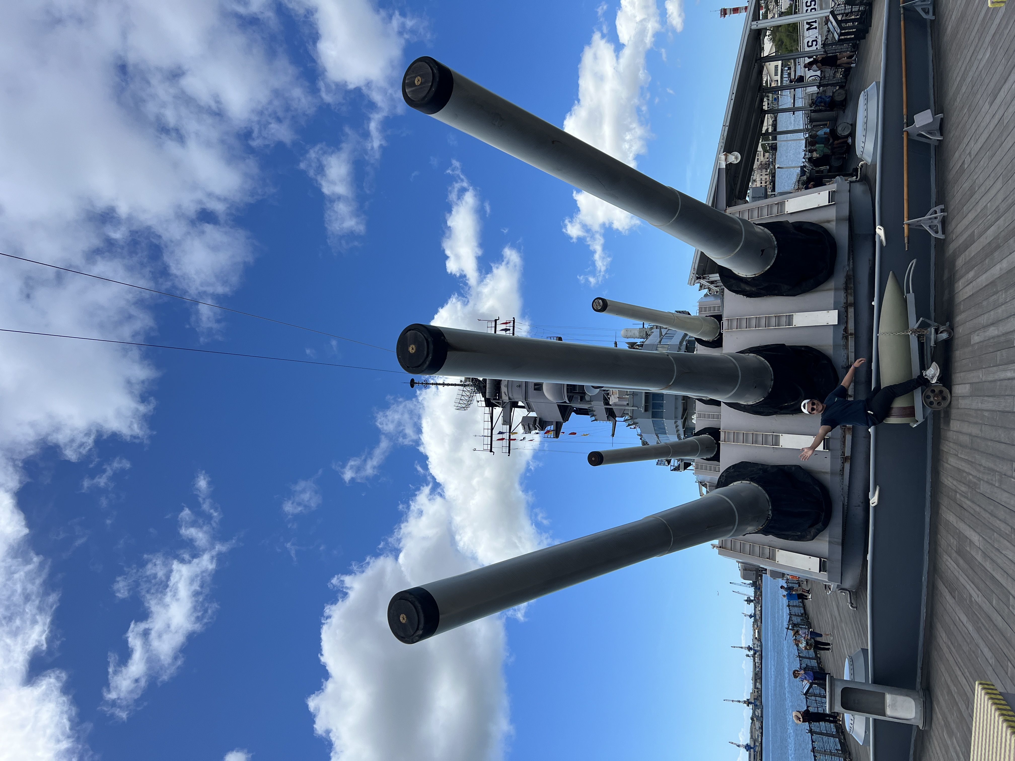 Nico sitting on a practice shell in front of the USS Missouri’s three 16-inch gun barrels.